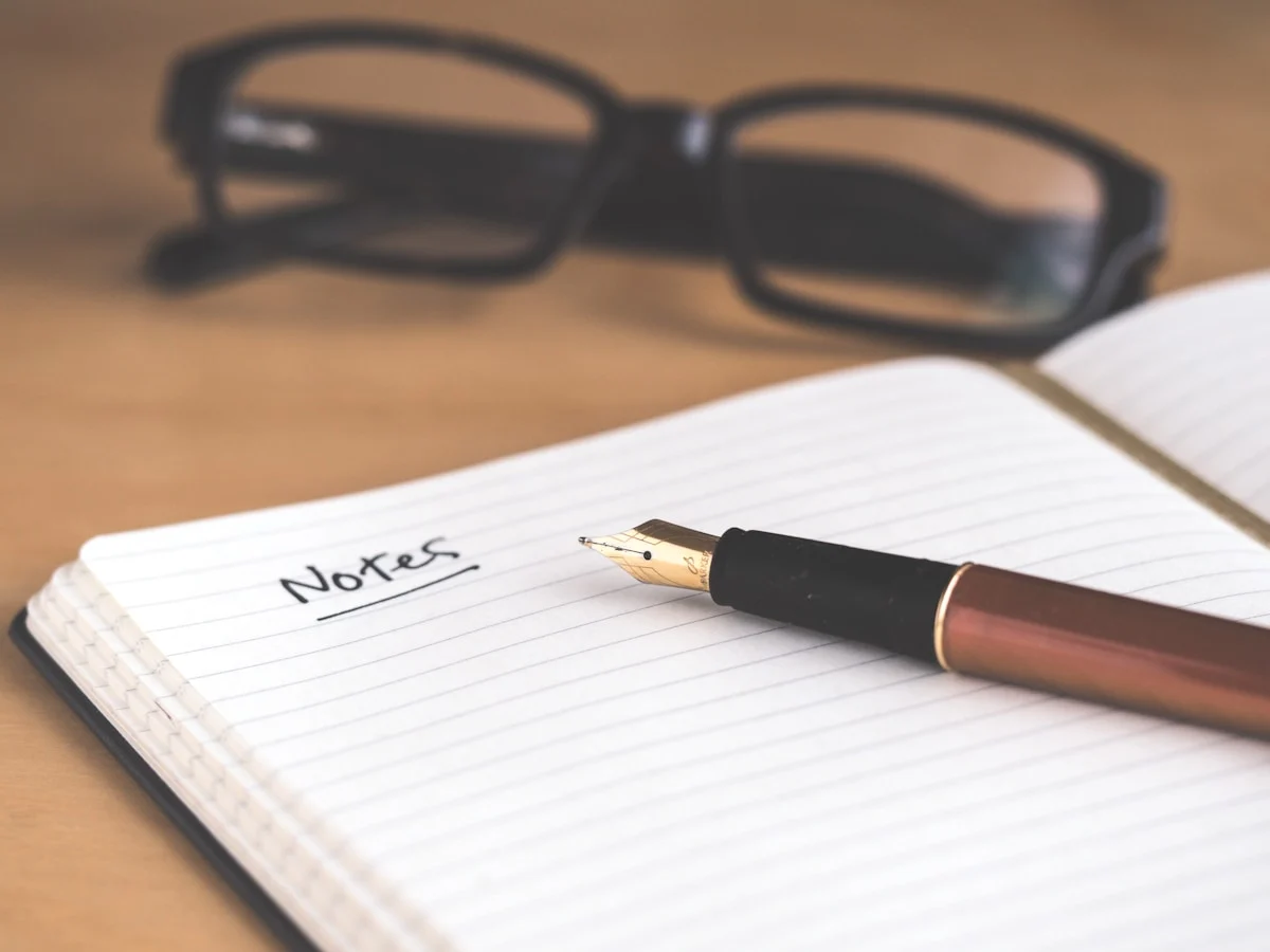 An open notebook with handwritten pages and a pen