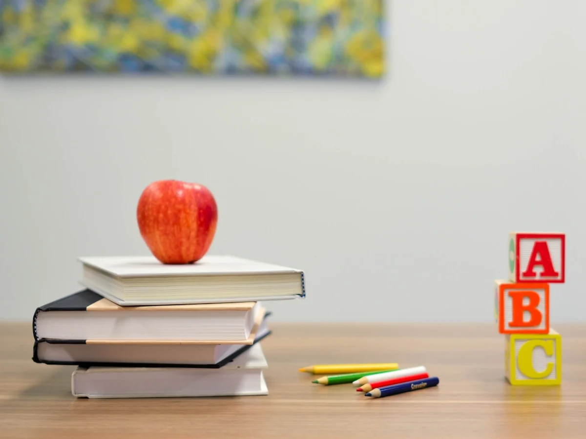 A desk with notebooks, books, and a warm lamp